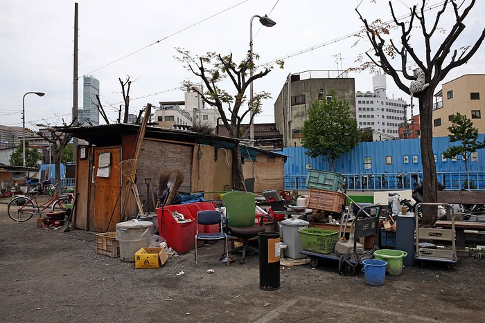 OSAKA, JAPAN - APRIL 24: A homeless woman pushes a wheelchair past the slum area of Kamagasaki on April 24, 2016 in Osaka, Japan. Kamagasaki, a district in Japans second largest city Osaka, is home to around 25,000 day labourers, jobless and homeless most of whom start each day hoping for an offer of manual labour and end it queuing for a ticket to access the shelter.  (Photo by Carl Court/Getty Images)
