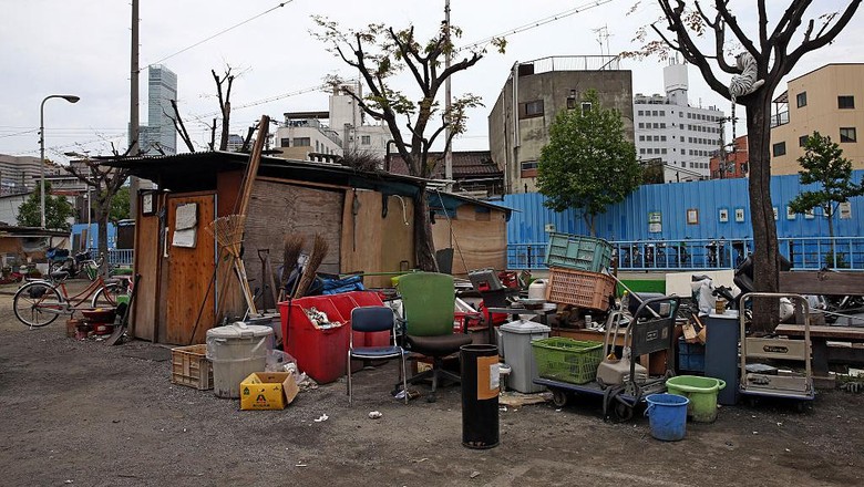 OSAKA, JAPAN - APRIL 24: A homeless woman pushes a wheelchair past the slum area of Kamagasaki on April 24, 2016 in Osaka, Japan. Kamagasaki, a district in Japans second largest city Osaka, is home to around 25,000 day labourers, jobless and homeless most of whom start each day hoping for an offer of manual labour and end it queuing for a ticket to access the shelter.  (Photo by Carl Court/Getty Images)