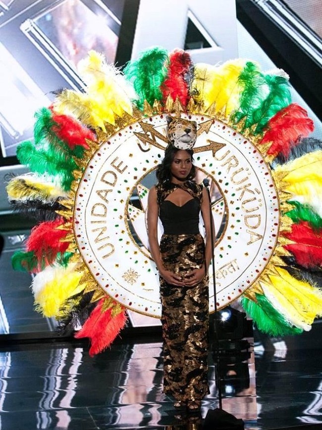 Shauna Ramdyhan, Miss Universe Guyana 2015 tampil dengan dress yang didominasi oleh warna hitam dan emas. Tak ingin monoton, hiasan kepala berupa topeng harimau melengkapi penampilannya. Selain itu, lingkaran besar yang dihiasi dengan bulu-bulu berwarna merah, kuning, hijau yang merupakan warna bendera Guyana menjadi highlight dari penampilannya. Foto: Facebook Miss Universe