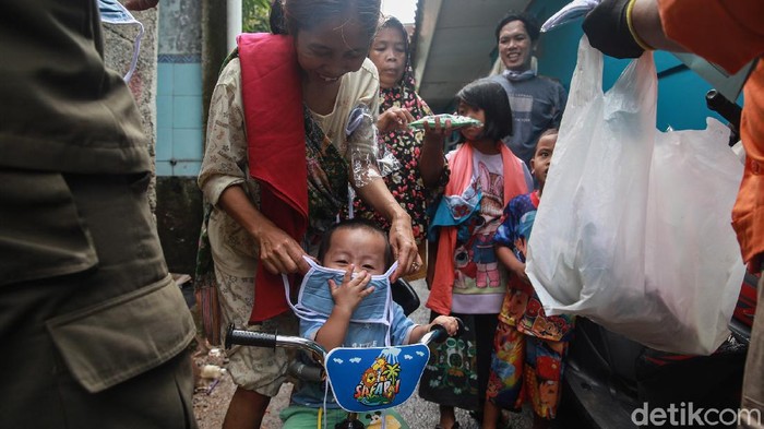 Petugas Kelurahan Ciganjur membagikan masker gratis kepada warga yang terdampak longsor sehingga menutupi aliran sungai di RT 004/002, Jl Damai, Ciganjur, jakarta Selatan, Senin (12/10/2020).