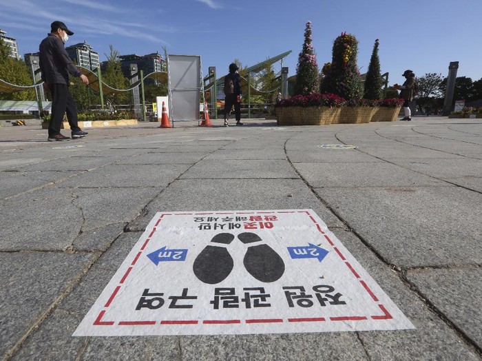 A social distancing sign is seen on the ground to help curb the spread of the coronavirus at a park in Goyang, South Korea, Tuesday, Oct. 6, 2020. The signs read: 