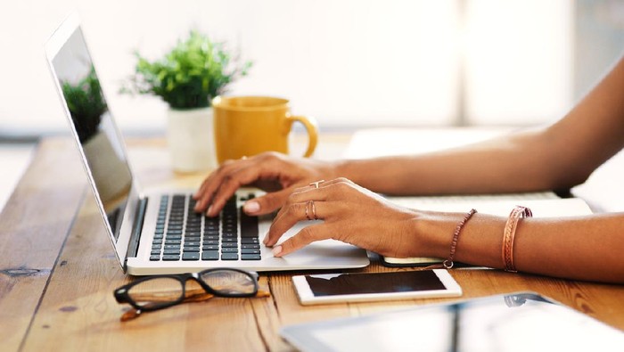 Cropped shot of an unrecognizable businesswoman sitting alone and typing on her laptop during the day at home