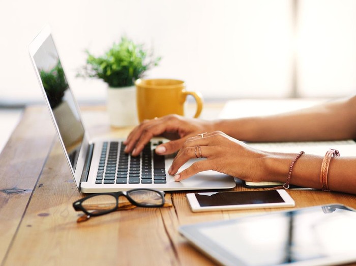 Cropped shot of an unrecognizable businesswoman sitting alone and typing on her laptop during the day at home