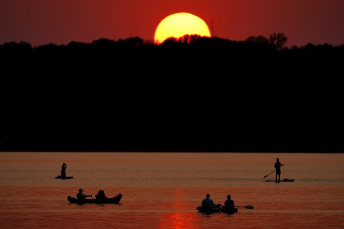 Indahnya Matahari Terbenam di Danau Kansas People watch the sunset while boating on Shawnee Mission Lake, Friday, Oct. 9, 2020, in Shawnee, Kan. Sunsets continue to be more vibrant than usual as smoke from western wildfires continue to drift across the country. (AP Photo/Charlie Riedel)