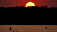 Orang-orang menyaksikan matahari terbenam sambil berperahu di Danau Shawnee Mission, Kansas.