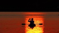 Seorang pria mengambil foto matahari terbenam saat berperahu di Danau Shawnee Mission, Kansas.  