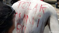 Seorang pendemo mengecat tubuhnya dengan tulisan tolak omnibus law