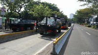 Sejumlah mobil taktis polisi seperti security barrier, Barracuda, dan water cannon terparkir di sepanjang jalan Pintu Barat Laut Monas. 