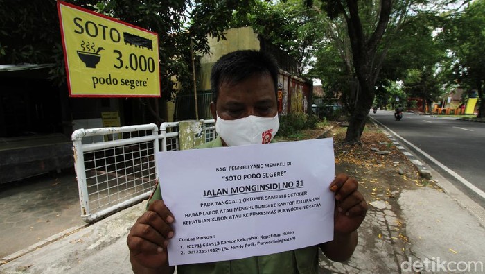 Plt Lurah Kepatihan Kulon bersama petugas babinsa dan linmas memasang pemberitahuan di depan warung Soto Podo Segere, Surakarta, Selasa (13/10/2020).