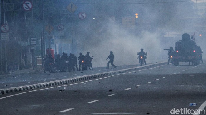 Massa berlarian usai dibubarkan pasukan Brimob dengan menggunakan gas air mata di Gambir, Jakarta, Selasa (13/10/2020).