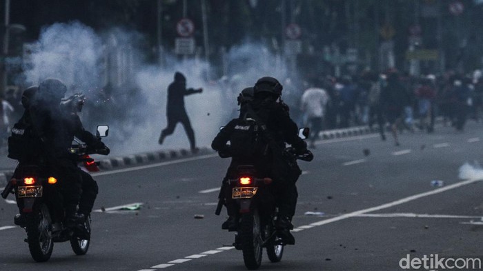 Massa berlarian usai dibubarkan pasukan Brimob dengan menggunakan gas air mata di Gambir, Jakarta, Selasa (13/10/2020).
