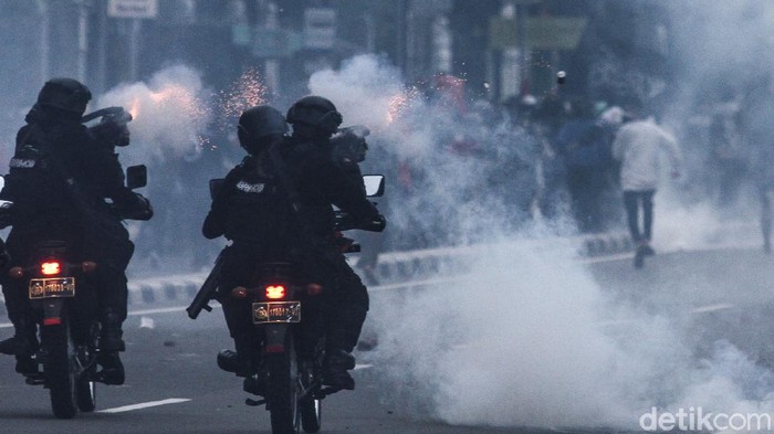 Massa berlarian usai dibubarkan pasukan Brimob dengan menggunakan gas air mata di Gambir, Jakarta, Selasa (13/10/2020).
