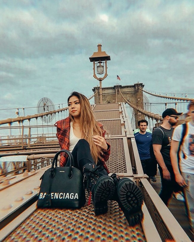 Berpose di Brooklyn Bridge, New York City, Clarissa menebar pesonanya dengan gaya grunge yang terdiri atasan putih berbelahan dada rendah, jaket merah, kotak-kotak, celana skinny, boots hitam, dan tas Balenciaga. (Foto: Instagram/@clarissatanoe)