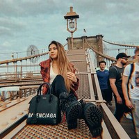 Berpose di Brooklyn Bridge, New York City, Clarissa menebar pesonanya dengan gaya grunge yang terdiri atasan putih berbelahan dada rendah, jaket merah, kotak-kotak, celana skinny, boots hitam, dan tas Balenciaga. (Foto: Instagram/@clarissatanoe)