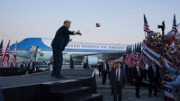 Calon Presiden Petahana Amerika Serikat, Donald Trump, melemparkan masker ke kerumunan pendukung saat ia tiba untuk kampanye di Bandara Internasional Orlando Sanford, Florida.  