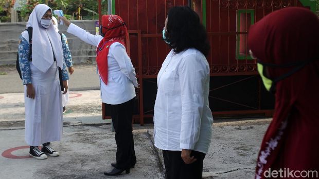 Guru melakukan pengecekan suhu tubuh pada Siswa-siswi Sekolah Menengah Pertama Negeri 1 Gantiwarno, Klaten, saat memasuki area sekolah pada saat uji coba sekolah tatap muka dengan standar protokol kesehatan ketat di Gantiwarno, Klaten, Jawa Tengah.
