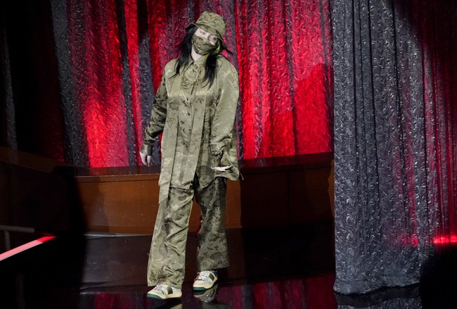 Billboard Music Awards 2020 tetap digelar di Dolby Theatre, Los Angeles, Rabu (14/10/2020), meski tanpa penonton karena pandemi COVID-19. Salah satu musisi kondang yang muncul adalah Billie Eilish. Seperti biasa, ia mengenakan kemeja dan celana serba longgar. Kali ini, busana keluaran Gucci tersebut dihiasi motif floral dan berwarna hijau pekat. Sebuah masker dan bucket hat senada ikut menemani gaya penyanyi yang saat itu memenangkan penghargaan untuk kategori Top 200 Album. (Foto: Chris Pizzello/AP)