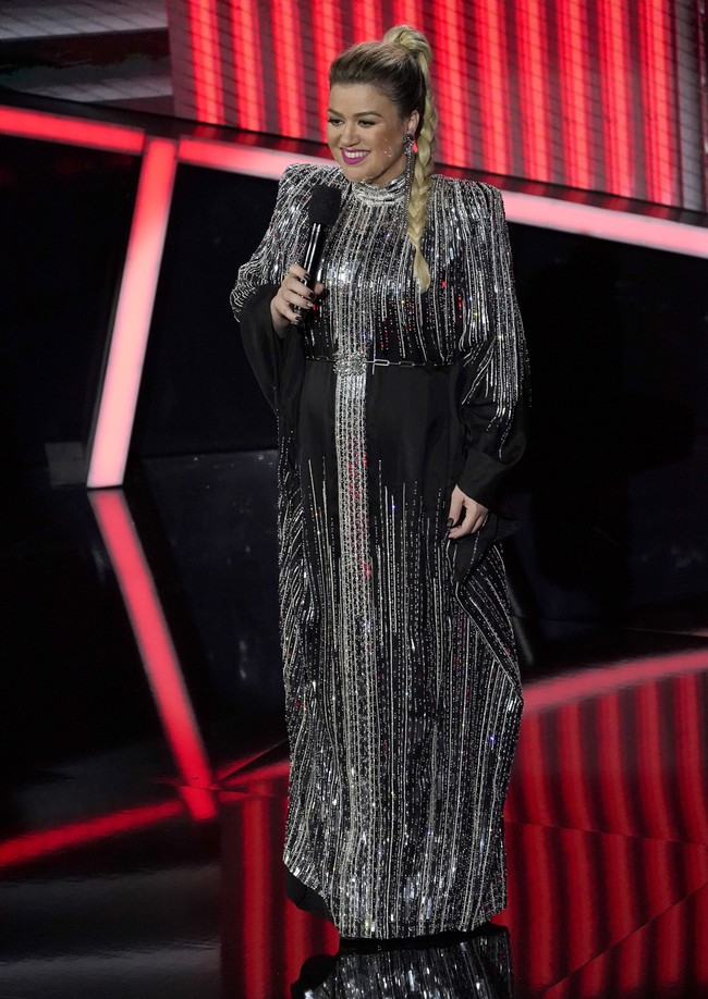 Kembali ditunjuk sebagai host, Kelly Clarkson juga tak kalah stylish. Gaun hitam bernuansa art deco yang dihiasi embellishment geometris yang menyala dan belt beraksen rantai menjadi salah satu pilihan jebolan American Idol itu. (Foto: Chris Pizzello/AP)