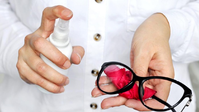 Women hand  holding white spray bottle cleaning trendy black glasses lens with red microfiber tissue.healthcare, vision and medicine concept