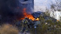 Petugas pemadam kebakaran berusaha memadamkan api dari mobil yang terbakar.
