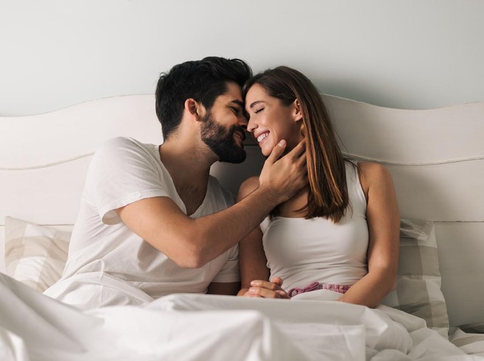 Affectionate young couple relaxing in bed and having a romantic moment