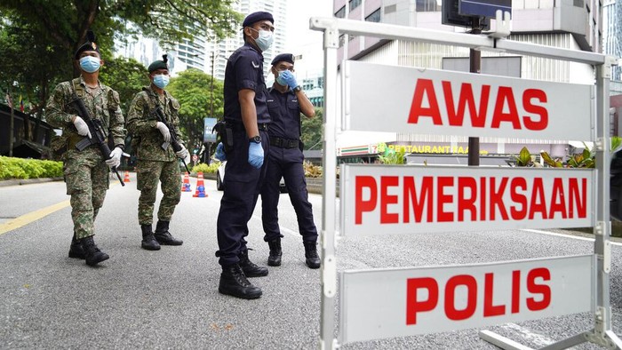 Police officers check vehicles at a roadblock to ensure that people abide by a movement control order on the outskirts of Kuala Lumpur, Malaysia, Wednesday, Oct. 14, 2020. Malaysia will restrict movements in its biggest city Kuala Lumpur, neighboring Selangor state and the administrative capital of Putrajaya from Wednesday to curb a sharp rise in coronavirus cases. (AP Photo/Vincent Thian)