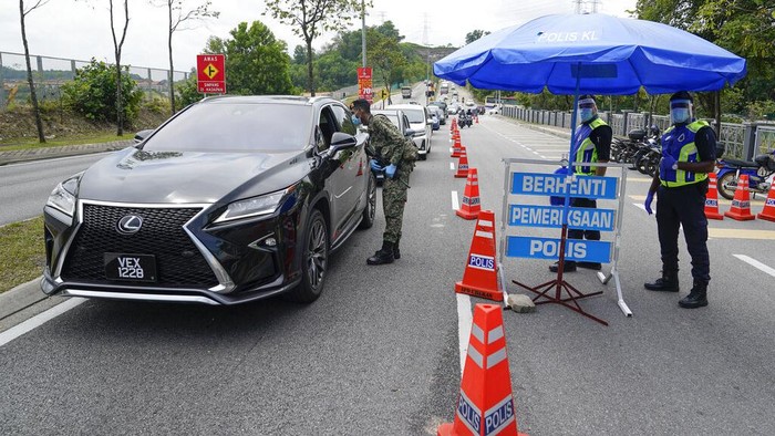 Kondisi Lalu Lintas Saat Kuala Lumpur Lockdown Lagi Police officers check vehicles at a roadblock to ensure that people abide by a movement control order on the outskirts of Kuala Lumpur, Malaysia, Wednesday, Oct. 14, 2020. Malaysia will restrict movements in its biggest city Kuala Lumpur, neighboring Selangor state and the administrative capital of Putrajaya from Wednesday to curb a sharp rise in coronavirus cases. (AP Photo/Vincent Thian)