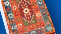 Kue bermotif permadani gaya Rusia lainnya dikreasikan dengan warna dasar oranye. Sekelilingnya diberikan motif tribal dengan paduan warna hijau, merah, biru, dan putih. Foto: Instagram @alanajonesmann