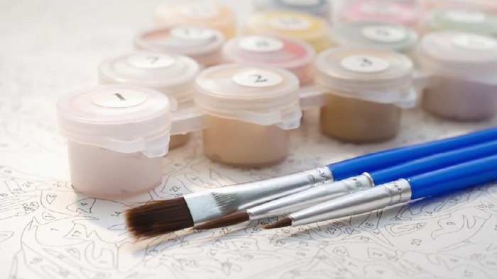 Female hand coloring paint by numbers picture. Creative hobby. Leisure activity at home during self-isolation COVID-19