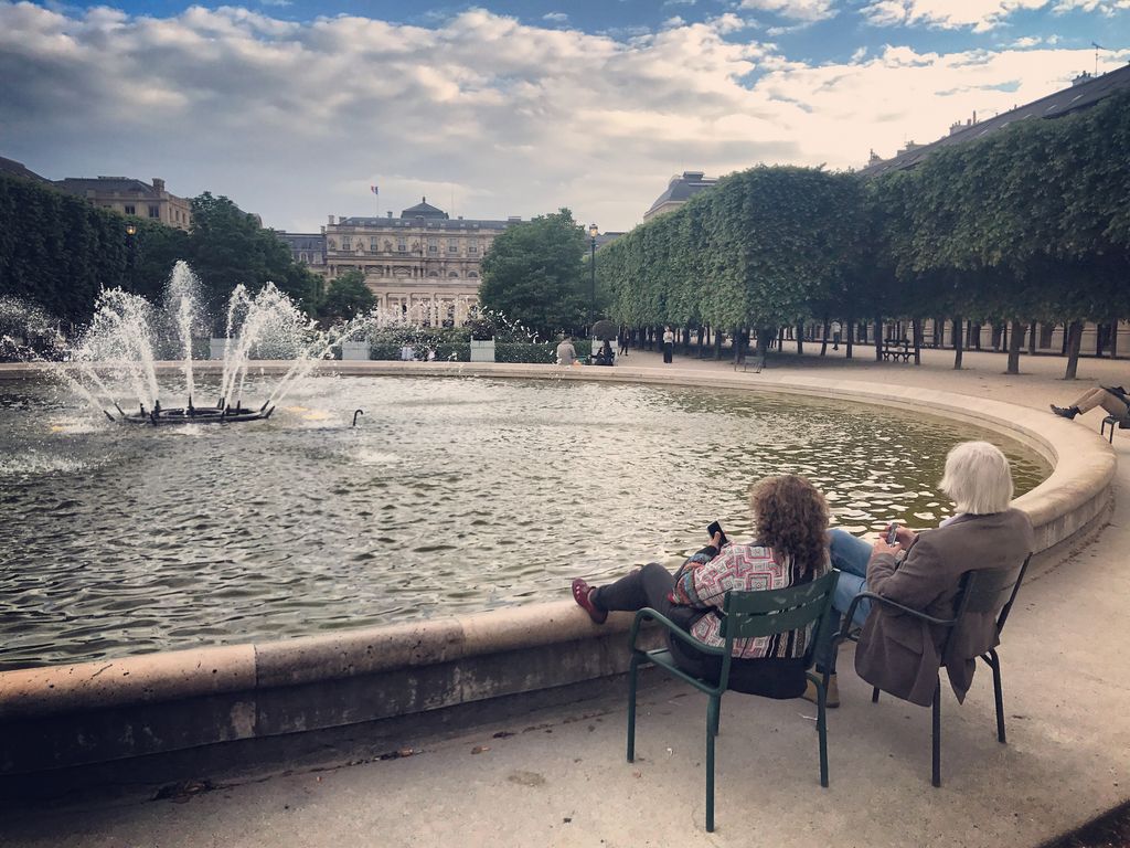 Warga bersantai dan menikmati sore yang hangat di Paris Jardin du Palais-Royal