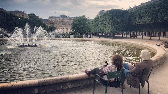 Warga bersantai dan menikmati sore yang hangat di Paris Jardin du Palais-Royal