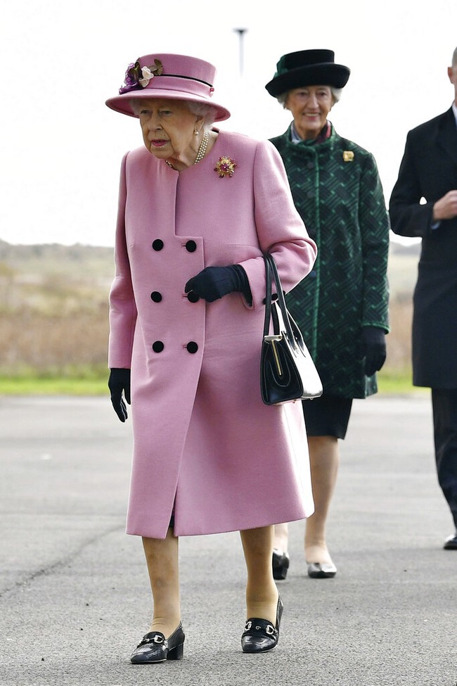 Ratu Elizabeth II muncul dalam balutan coat berwarna pink yang senada dengan warna topinya. Untuk aksesori lain, ia memilih warna hitma. Mulai dari sarung tangan, hand bag, hingga sepatu bergaya loafer. (Foto: AP/Ben Stansall)