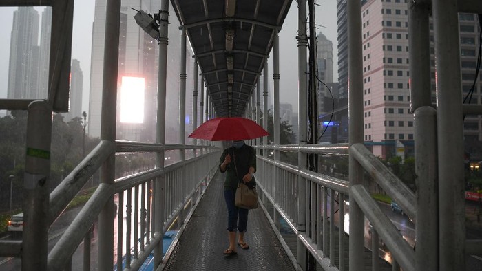 Seorang warga mengenakan jas hujan saat melintas di jembatan penyeberangan orang (JPO) di Senayan, Jakarta, Jumat (16/10/2020). Menurut Badan Meteorologi, Klimatologi dan Geofisika (BMKG) musim hujan di Indonesia telah berlangsung dari bulan Oktober dan diprediksi puncak musim hujan terjadi pada Januari hingga Februari 2021. ANTARA FOTO/Wahyu Putro A/wsj.