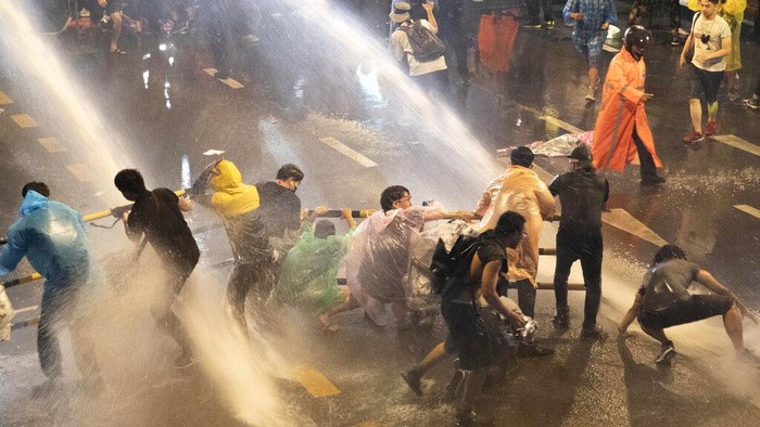 Potret Demonstran Thailand Ditembak Water Canon Police use water canons to try and disperse demonstrators from their protest venue in Bangkok, Thailand, Friday, Oct. 16, 2020. Thailand prime minister has rejected calls for his resignation as his government steps up efforts to stop student-led protesters from rallying in the capital for a second day in defiance of a strict state of emergency. (AP Photo/Sakchai Lalit)