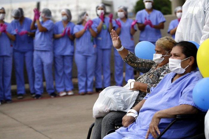 Medical workers embrace while they celebrate as the last three patients are released from a field hospital at the National Stadium Mane Garrincha, after recuperating from COVID-19, in Brasilia, Brazil, Thursday, Oct. 15, 2020. (AP Photo/Eraldo Peres)