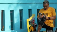 Aaro Chan sedang memakaikan baju ke salah satu monyetnya.