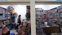 Seorang pedagang menata barang dagangan di dalam kiosnya.