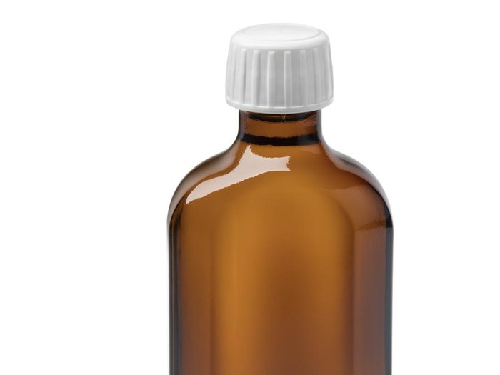 Bottle with cosmetic candlenut oil and nuts isolated on white background