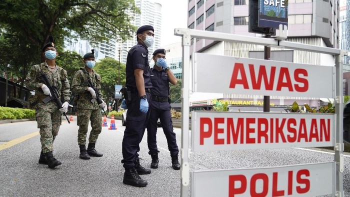 Malaysia Catat Rekor Tertinggi Kasus Corona Police officers check vehicles at a roadblock to ensure that people abide by a movement control order on the outskirts of Kuala Lumpur, Malaysia, Wednesday, Oct. 14, 2020. Malaysia will restrict movements in its biggest city Kuala Lumpur, neighboring Selangor state and the administrative capital of Putrajaya from Wednesday to curb a sharp rise in coronavirus cases. (AP Photo/Vincent Thian)