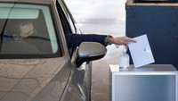 Tampak warga mengenakan sarung tangan plastik saat hendak memasukan surat suara ke kotak yang telah disediakan di layanan pemungutan suara drive in.