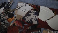 Pekerja membuat pola dan menggunting kain batik lukis sebagai bahan dasar masker.  