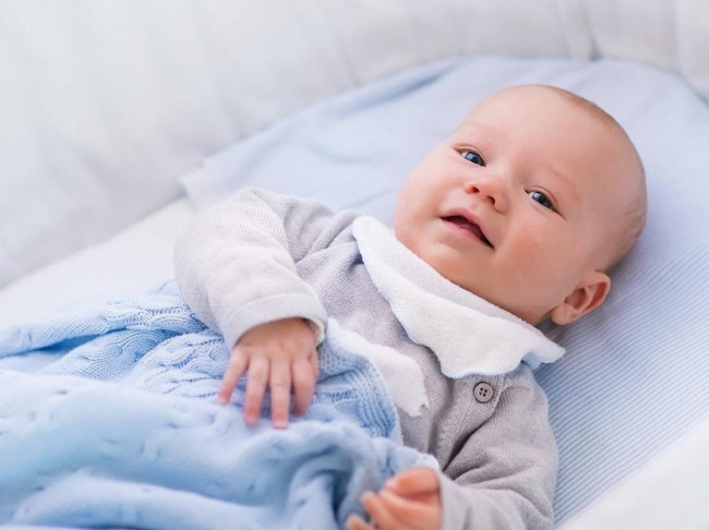 Newborn baby boy in bed. New born child sleeping under a white knitted blanket. Children sleep. Bedding for kids. Infant napping in bed. Healthy little kid shortly after birth. Cable knit textile.