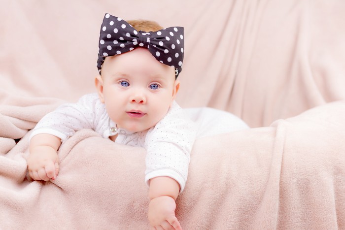 bayi perempuan Portrait of a beautiful baby girl with the black band on her head lying on the sofa