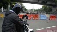 Pengendara sepeda motor menghentikan laju kendaraannya untuk mengabadikan pengamanan aksi di kawasan Istana Negara.