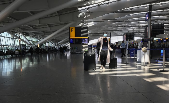 FILE - In this Tuesday, March 24, 2020 file photo, a woman wears a mask as she walks through a quieter than usual Heathrow Airport Terminal 5, in London. Air traffic is down 92% this year as travelers worry about catching COVID-19 and government travel bans and quarantine rules make planning difficult. One thing airlines believe could help is to have rapid virus tests of all passengers before departure. (AP Photo/Kirsty Wigglesworth, File)