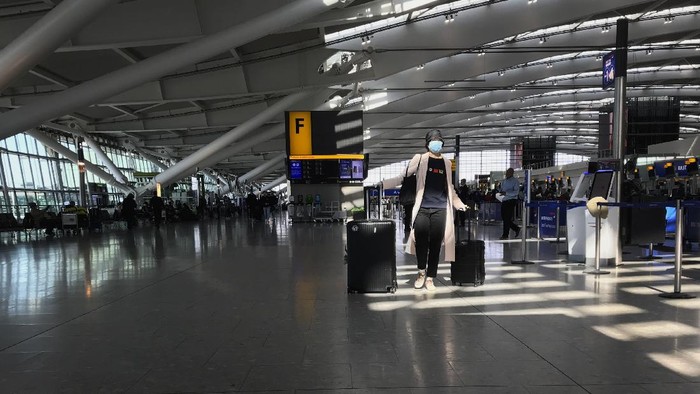 FILE - In this Tuesday, March 24, 2020 file photo, a woman wears a mask as she walks through a quieter than usual Heathrow Airport Terminal 5, in London. Air traffic is down 92% this year as travelers worry about catching COVID-19 and government travel bans and quarantine rules make planning difficult. One thing airlines believe could help is to have rapid virus tests of all passengers before departure. (AP Photo/Kirsty Wigglesworth, File)