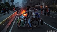 Di tengah demo, seorang penjula minuman masih berkeliling mencari cuan.