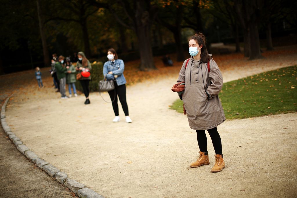 People, wearing masks and keeping social distance to prevent the spread of the coronavirus, wait in line to be tested in a Red Cross COVID-19 test center at Cinquantenaire park in Brussels, Monday, Oct. 19, 2020. Bars and restaurants across Belgium shut down for a month and a night-time curfew entered into force Monday in the hard-hit coronavirus country as health authorities warned of a possible sanitary 