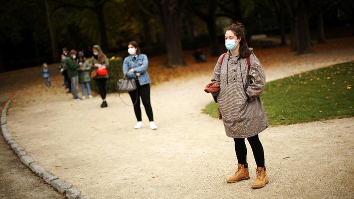 People, wearing masks and keeping social distance to prevent the spread of the coronavirus, wait in line to be tested in a Red Cross COVID-19 test center at Cinquantenaire park in Brussels, Monday, Oct. 19, 2020. Bars and restaurants across Belgium shut down for a month and a night-time curfew entered into force Monday in the hard-hit coronavirus country as health authorities warned of a possible sanitary 