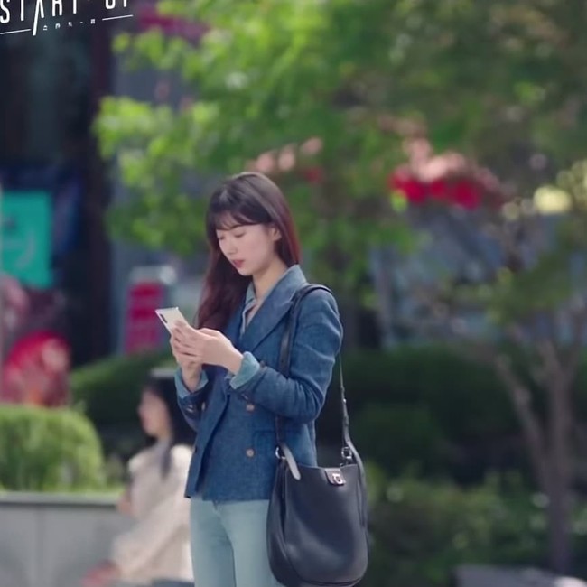 Pada adegan ini, Bae Suzy terlihat mengenakan blazer denim warna navy dan tas hitam. Foto: Dok. Start-Up/Netflix